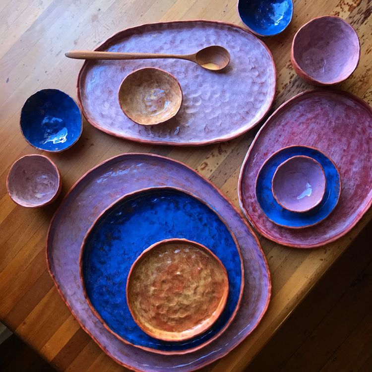 A selection of blue and purple ceramic plates and bowls arranged on a table
